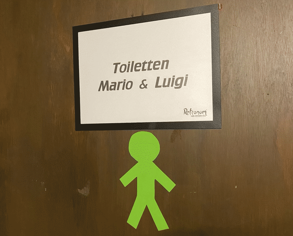 Toilettentür im Retronom mit dem Schild „Toiletten Mario & Luigi“ und einem grünen Strichmännchen
